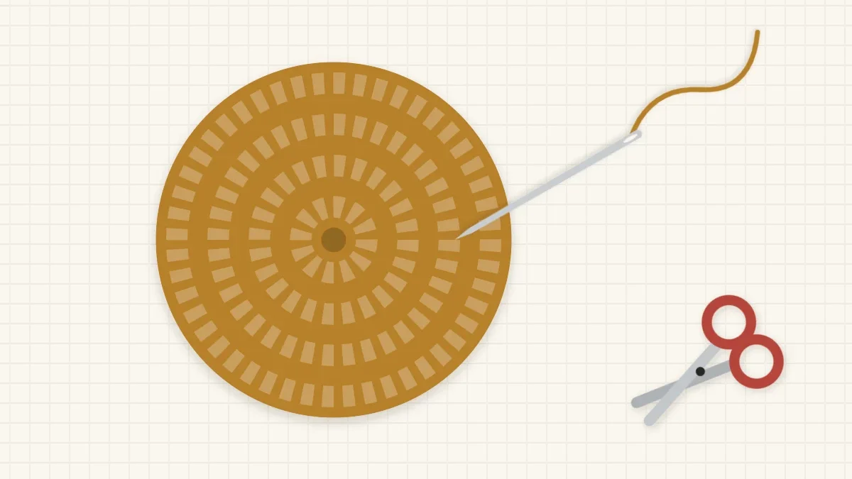 Back of a round coaster with a threaded yarn needle and scissors beside it