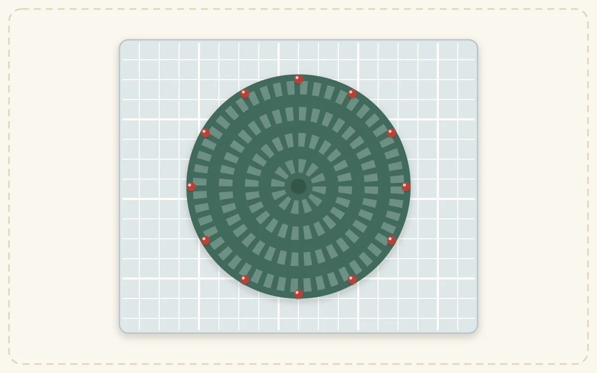 A round coaster pinned evenly around its edge to a gridded mat, with the pins shown as small round heads