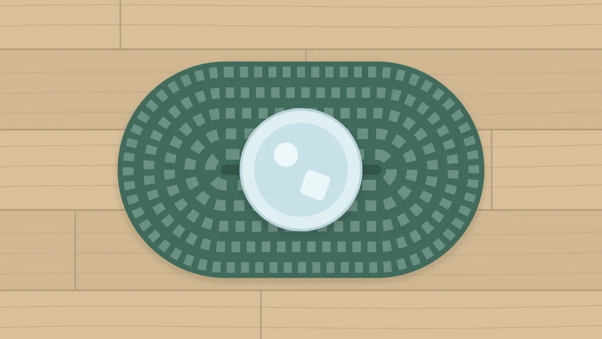 An oval coaster in sage with a tall glass standing on it